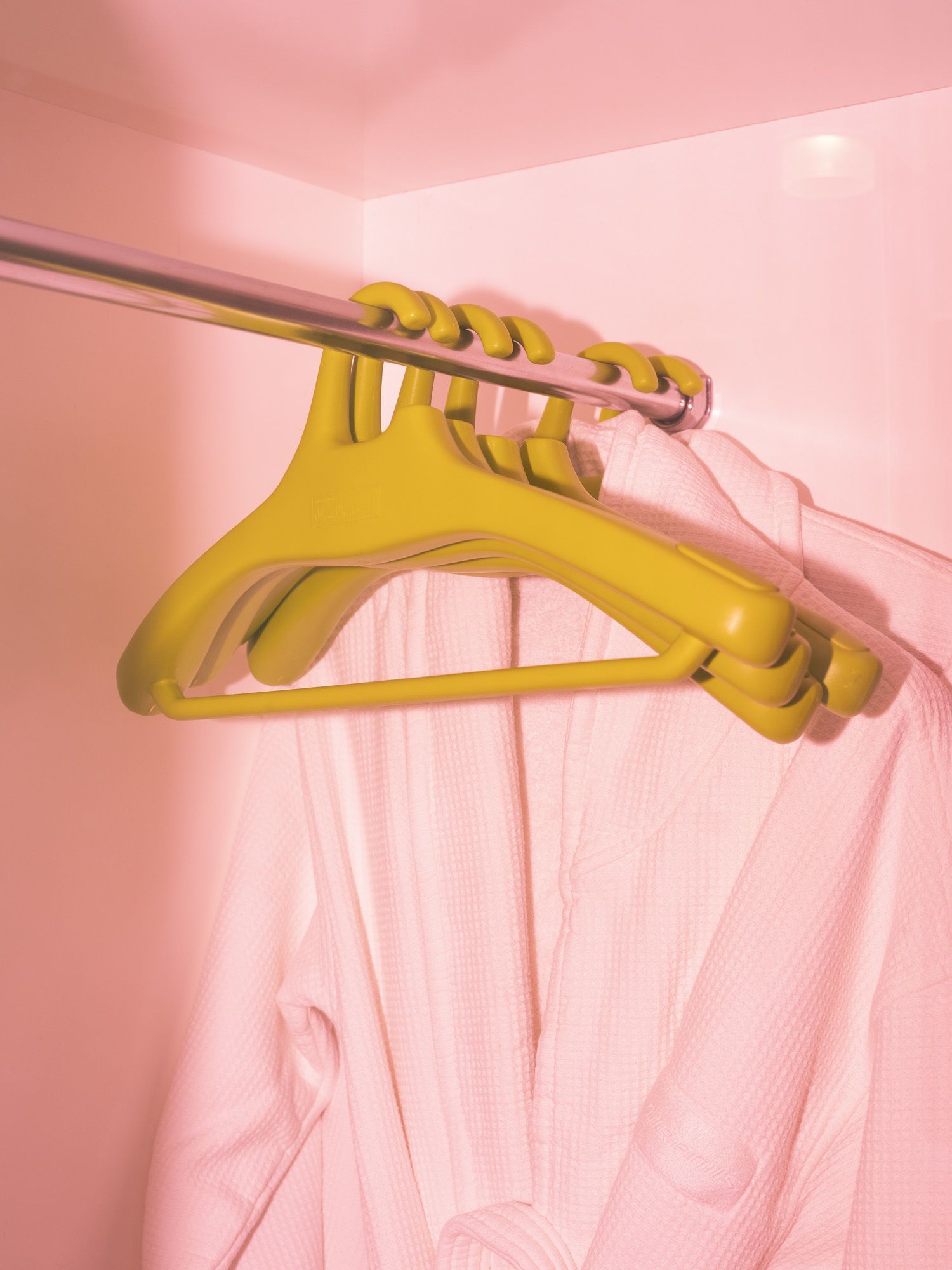 Una pared rosa con un perchero amarillo.