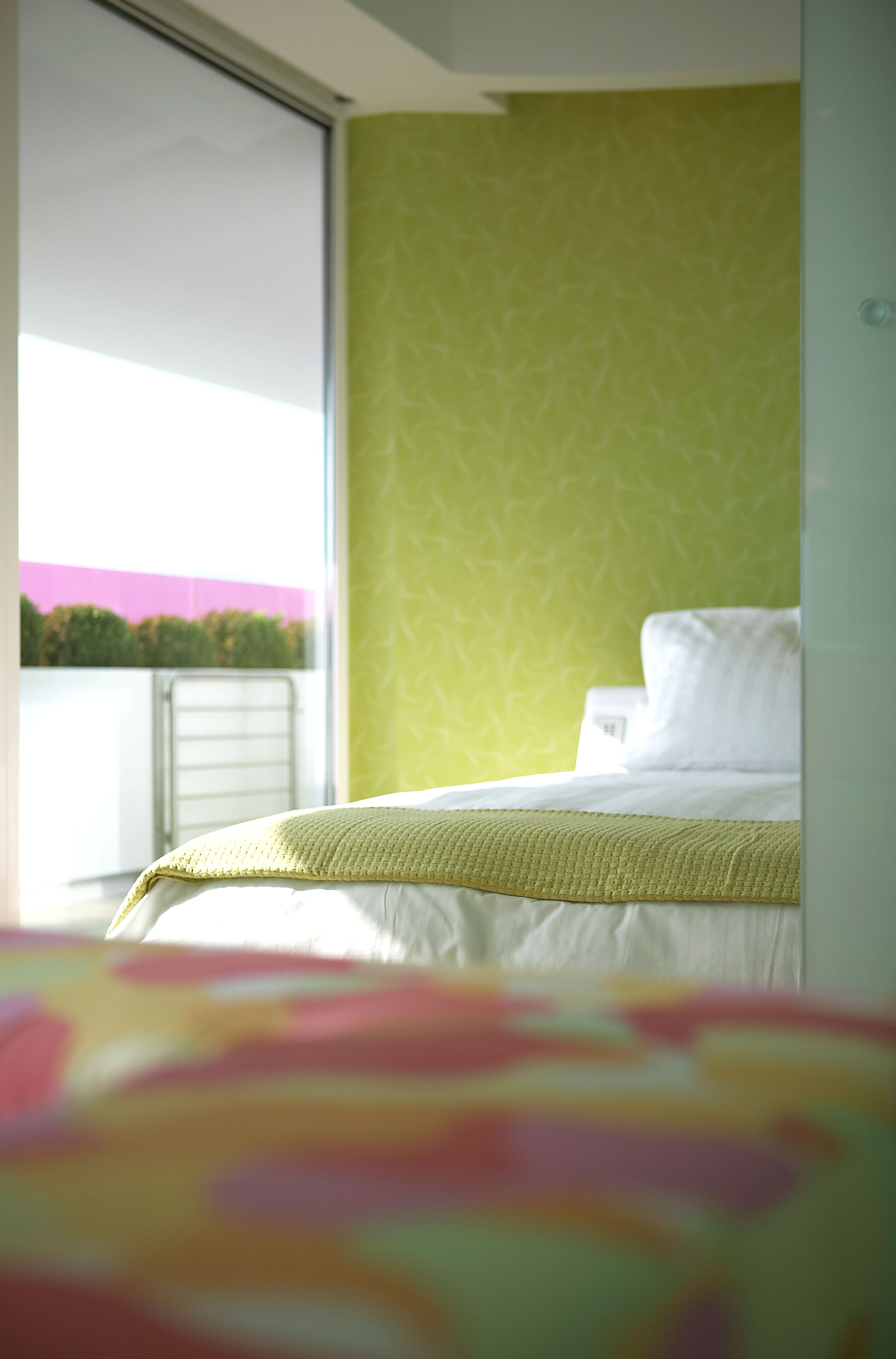 A bedroom with a bed, a window, and a view of greenery outside.