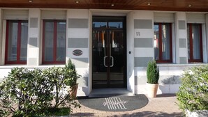 Ein Hotel mit moderner Gestaltung, mit einem gebogenen Dach, einer Glastür mit Metallgriff und einer Fußmatte mit dem Namen des Hotels.