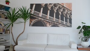 Ein weißes Sofa, ein Bücherregal und ein großes gerahmtes Bild der Gebäudefassade.