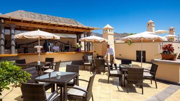 An outdoor patio with wicker furniture, umbrellas, and a bar area.