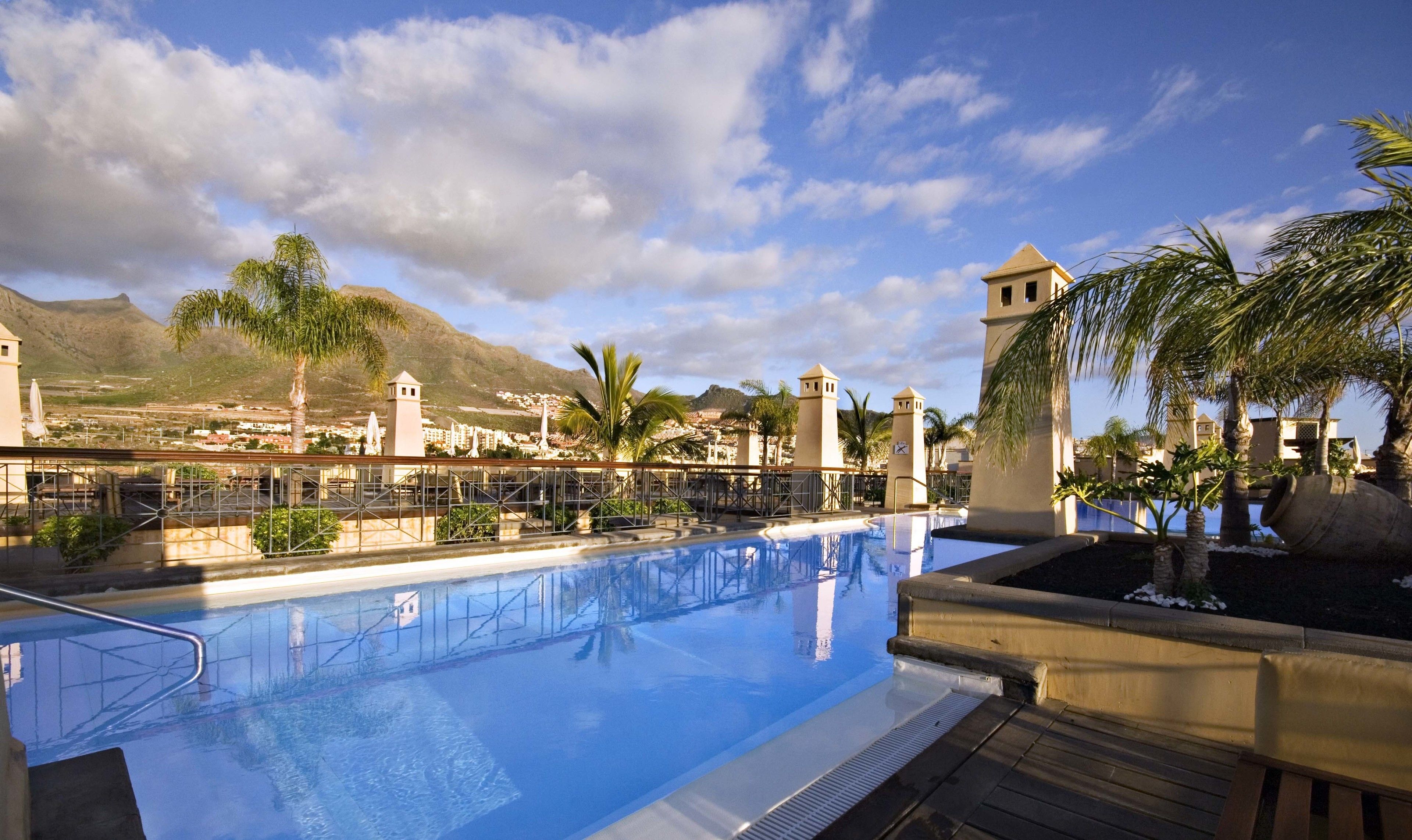 A swimming pool with a view of a mountainous landscape and a clear sky.