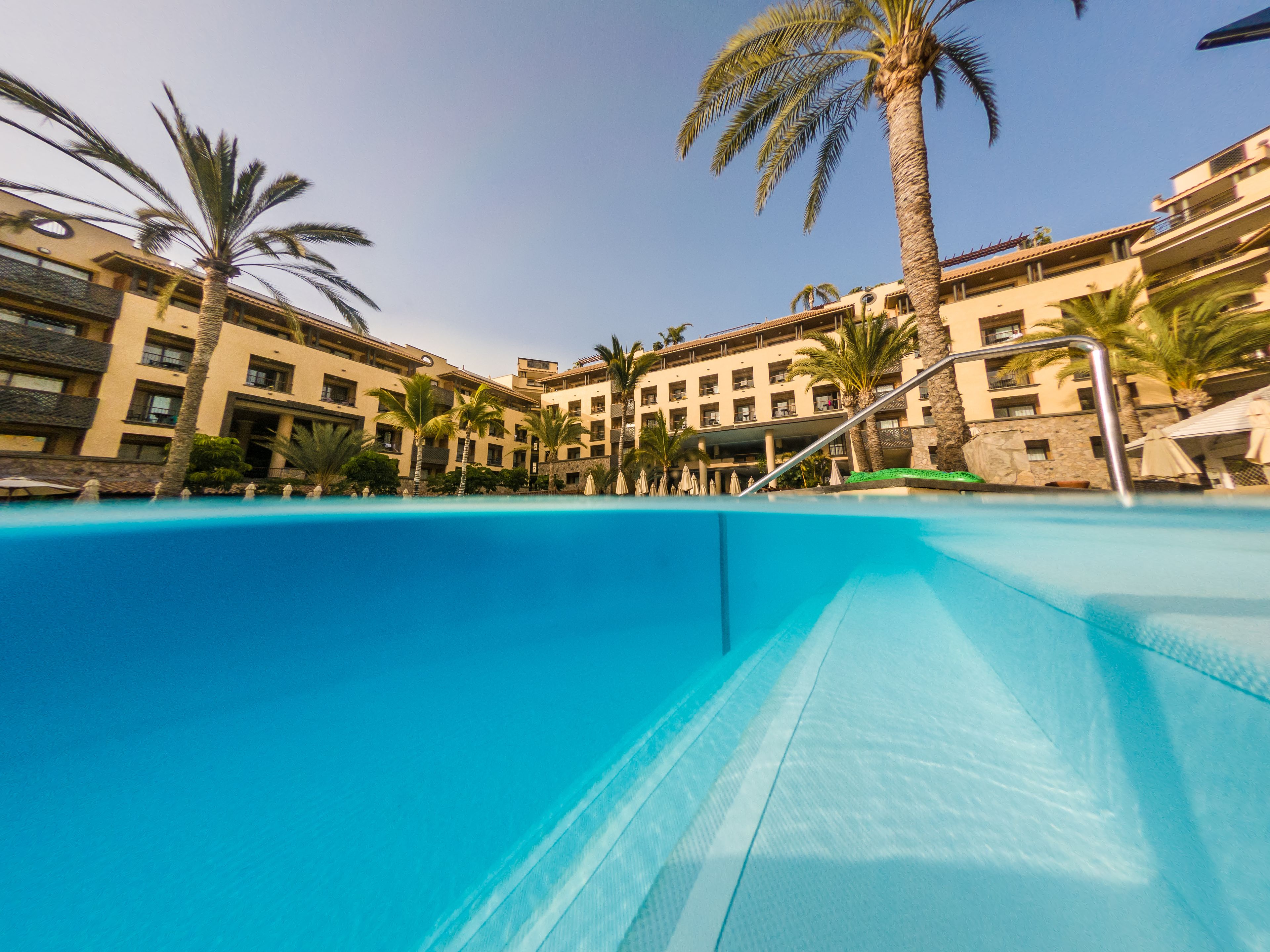 Piscina rodeada de palmeras y edificios de hotel.