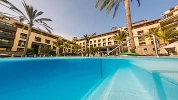 Piscina rodeada de palmeras y edificios de hotel.