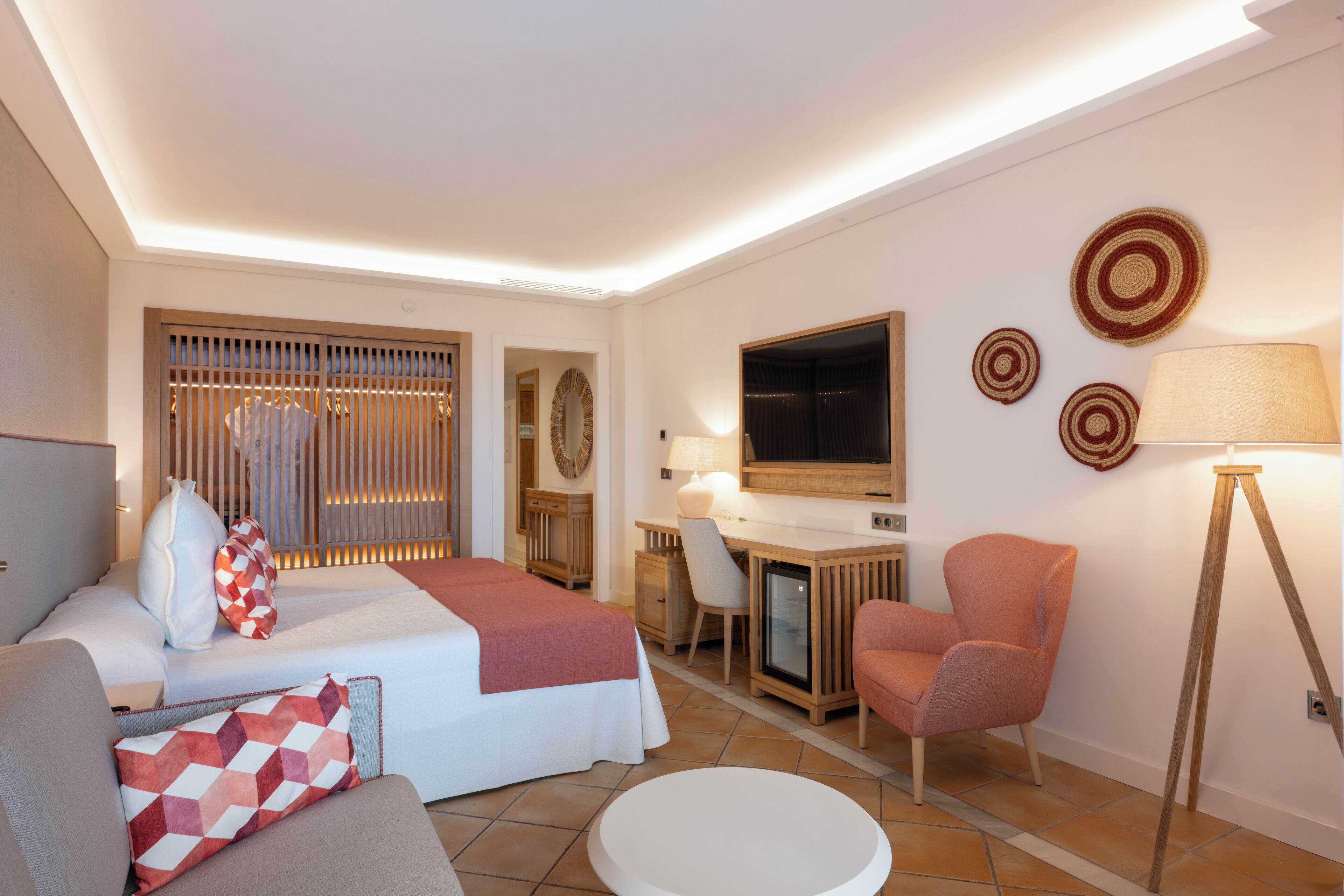 Una habitación de hotel moderna con una cama, un escritorio, una silla, un sofá y una lámpara.
