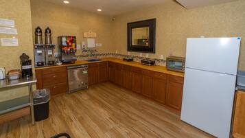 Una cocina con armarios de madera, lavavajillas, cafetera, tostadora y refrigerador.