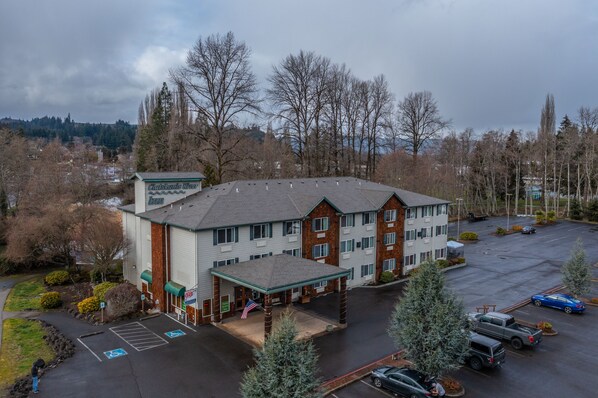 A multi-story hotel with a covered entrance and a parking lot. - Clatskanie River Inn (Clatskanie)