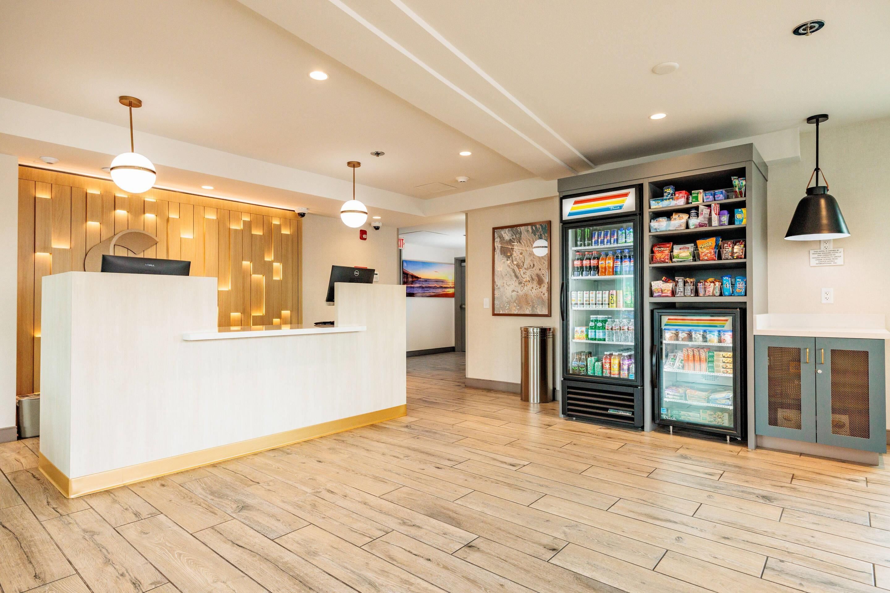A reception area with a wooden reception desk, a refrigerator stocked with beverages, and a vending machine.