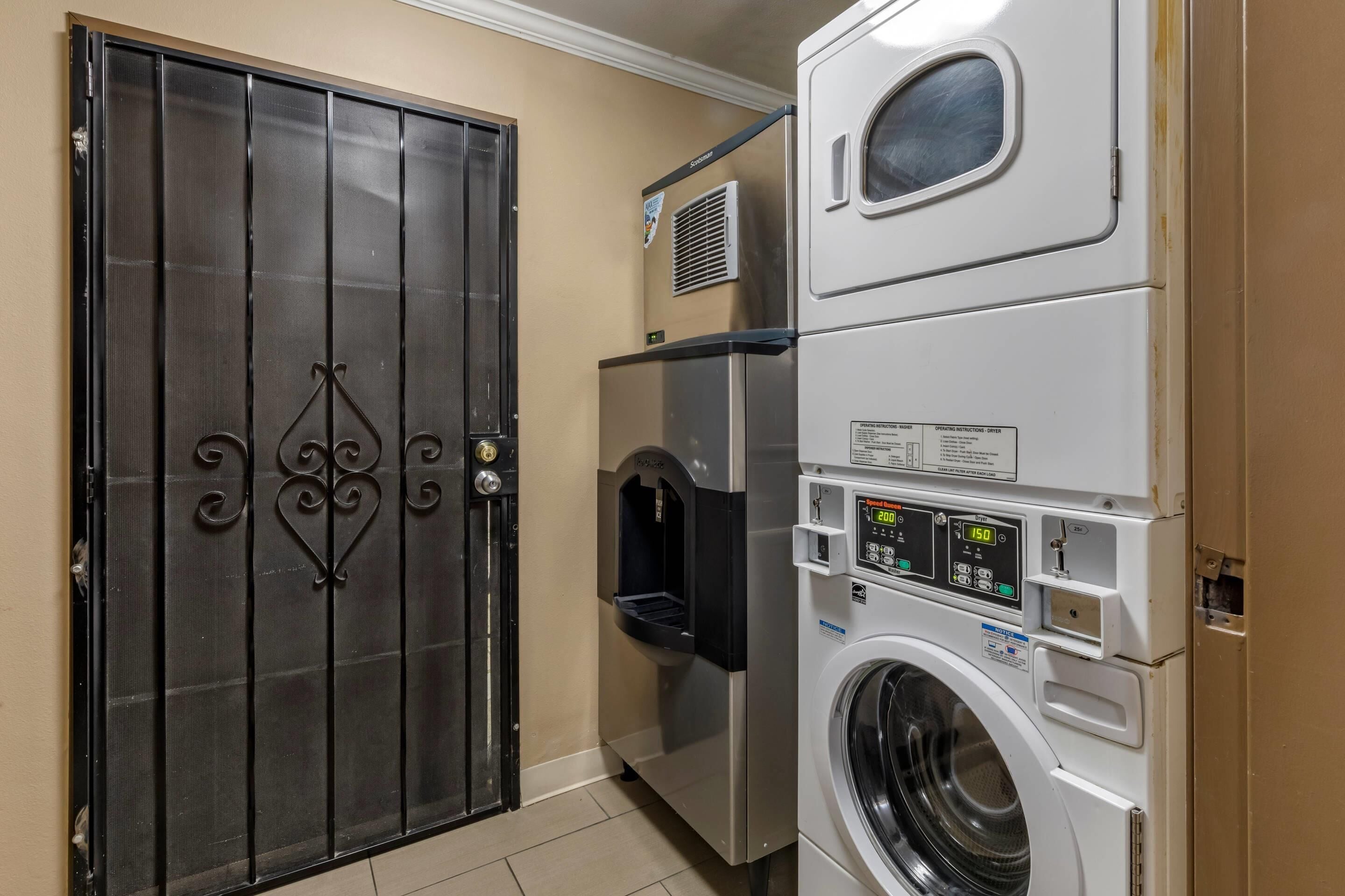 A laundry room with a large metal door, a stacked washer and dryer, and a water dispenser.