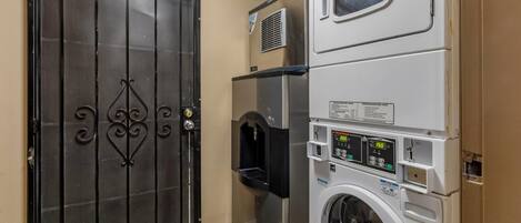 A laundry room with a large metal door, a stacked washer and dryer, and a water dispenser.