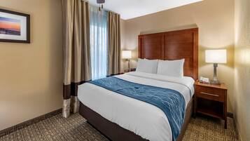 A hotel room with a large bed, two bedside tables with lamps, a ceiling fan, and a framed picture on the wall.