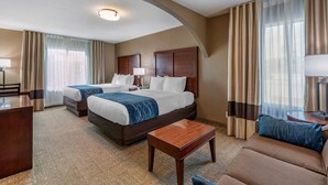 A hotel room with two beds, a sofa, a desk, and a lamp. - Comfort Inn & Suites Ventura Beach (Ventura)