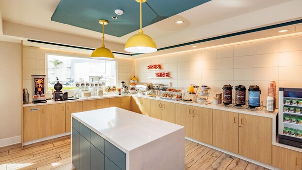 A modern kitchen with wooden cabinets, a central island, and a coffee station. - Comfort Inn & Suites Ventura Beach (Ventura)