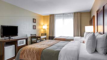 A hotel room with two beds, a TV, a mini-fridge, a desk, and a chair.