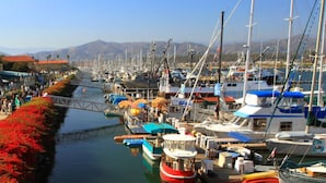 A marina with boats docked along a canal, surrounded by buildings with red-tiled roofs and outdoor seating areas. - Comfort Inn & Suites Ventura Beach (Ventura)