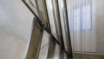 Un escalier au design moderne, doté d’une rampe en verre et d’un sol en marbre.