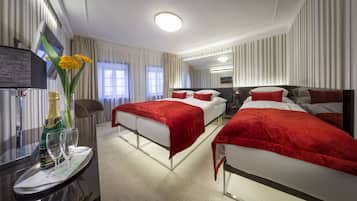 Habitación de hotel con dos camas, televisión, minibar y un amplio ventanal con cortinas.