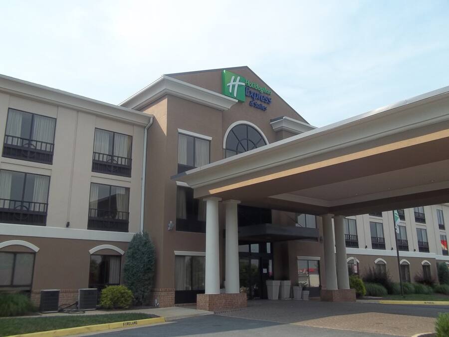 A Holiday Inn Express & Suites building with a covered entrance, large windows, and a fire lane.