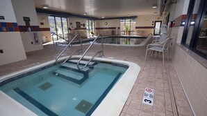 An indoor swimming pool with clear water, tiled walls, and a lifeguard chair. - Hampton Inn Oneonta (Oneonta)