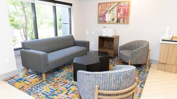 A living room with a grey sofa, a patterned armchair, a black coffee table, and a colorful rug.