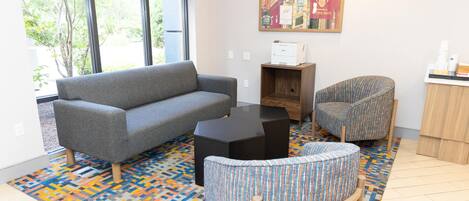A living room with a grey sofa, a patterned armchair, a black coffee table, and a colorful rug.