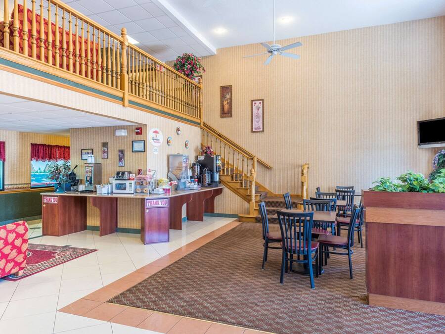A hotel lobby with a reception desk, a staircase, and a dining area.