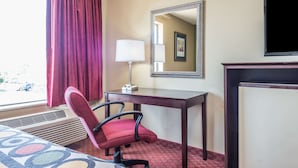 Une chambre d’hôtel équipée d’un lit, d’un bureau, d’une chaise, d’une lampe, d’un miroir et d’un téléviseur.