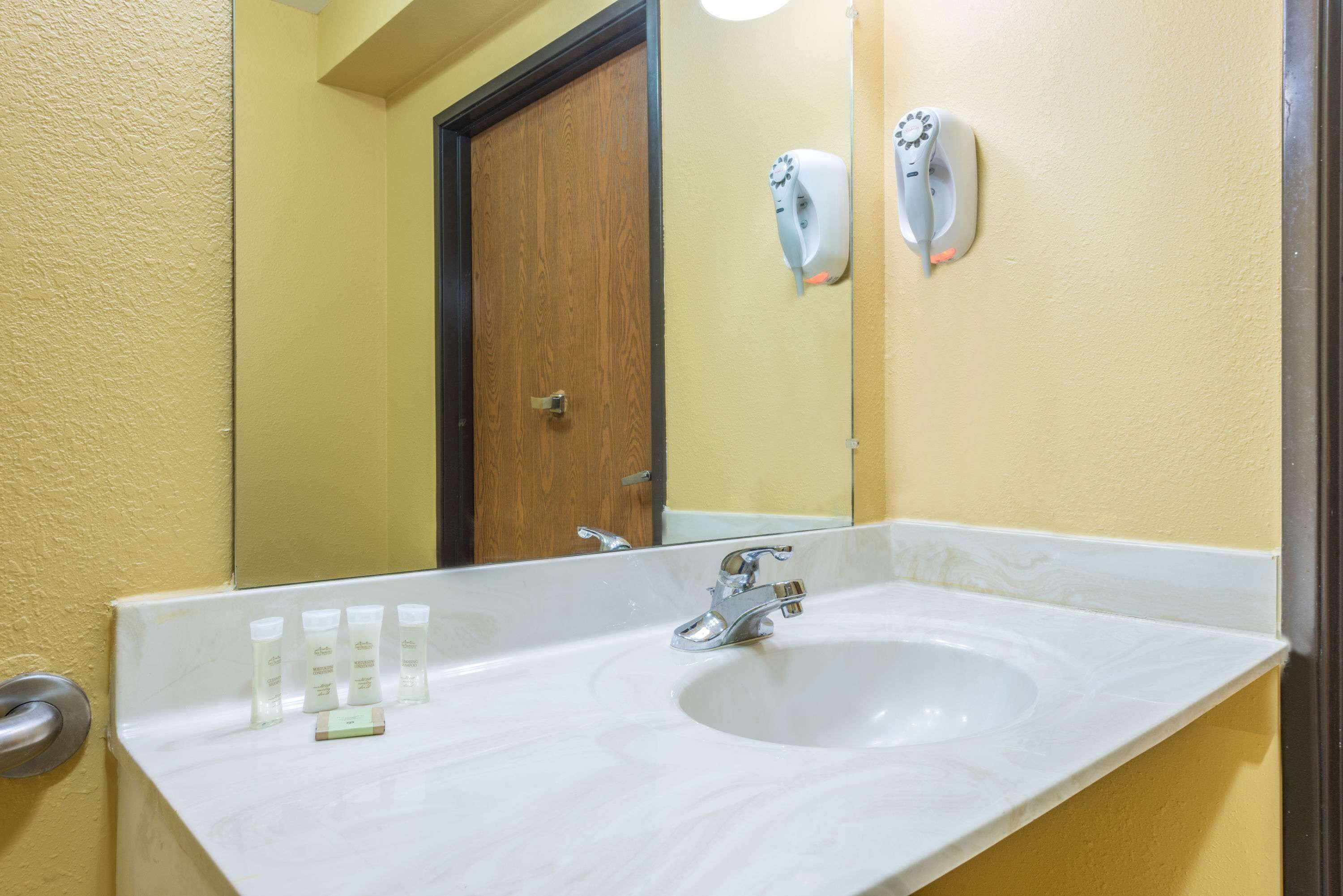 A bathroom with a white sink, a mirror, and a wooden door.
