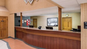 Un comptoir d’accueil en bois, deux ordinateurs portables HP, un téléphone et une photographie en noir et blanc encadrée accrochée au mur.