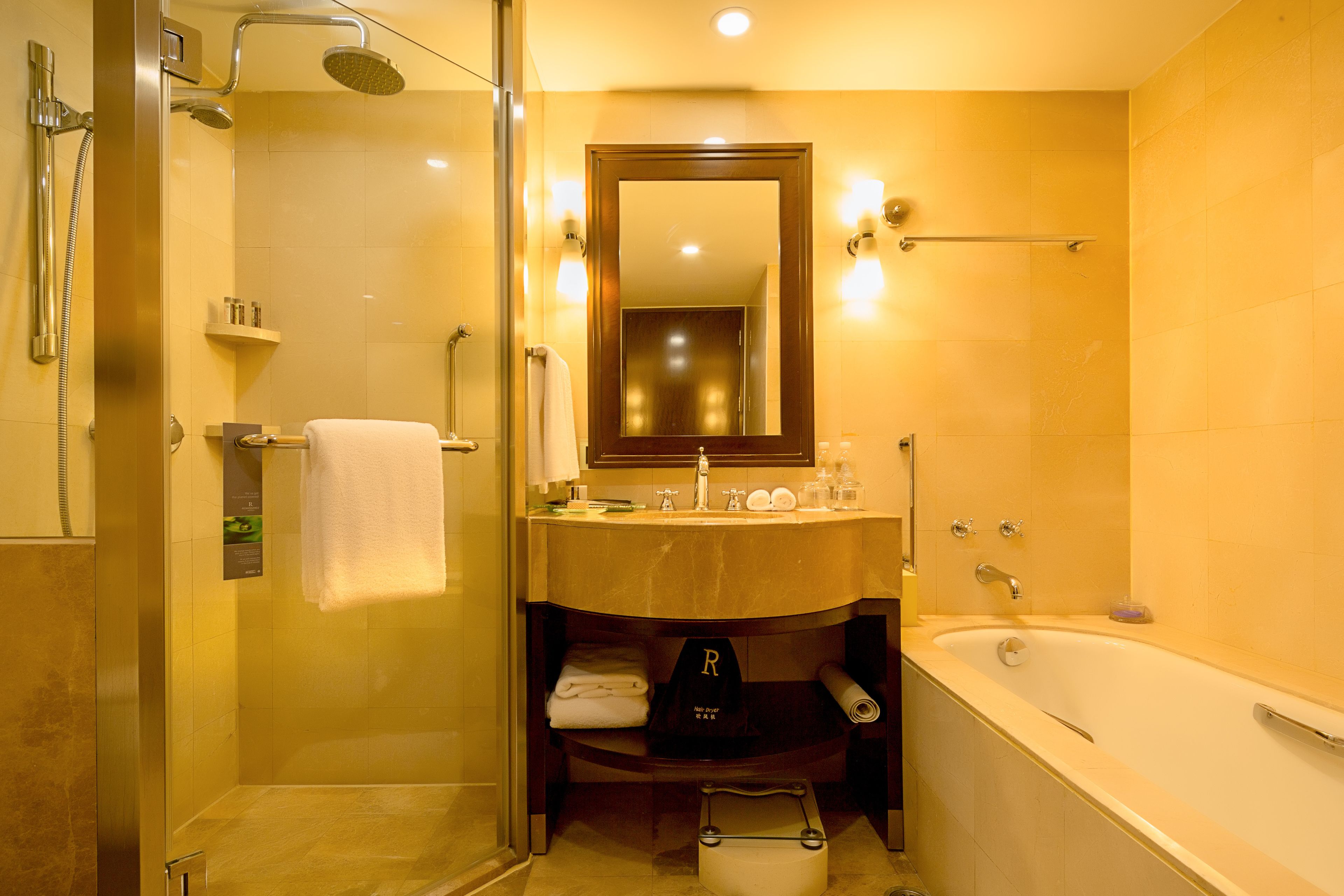 Een moderne badkamer met een douchecabine van glas, een grote spiegel en een bad.