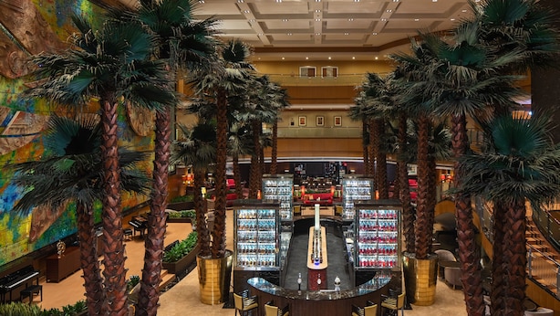 A bar area with a central bar, surrounded by palm trees and seating.