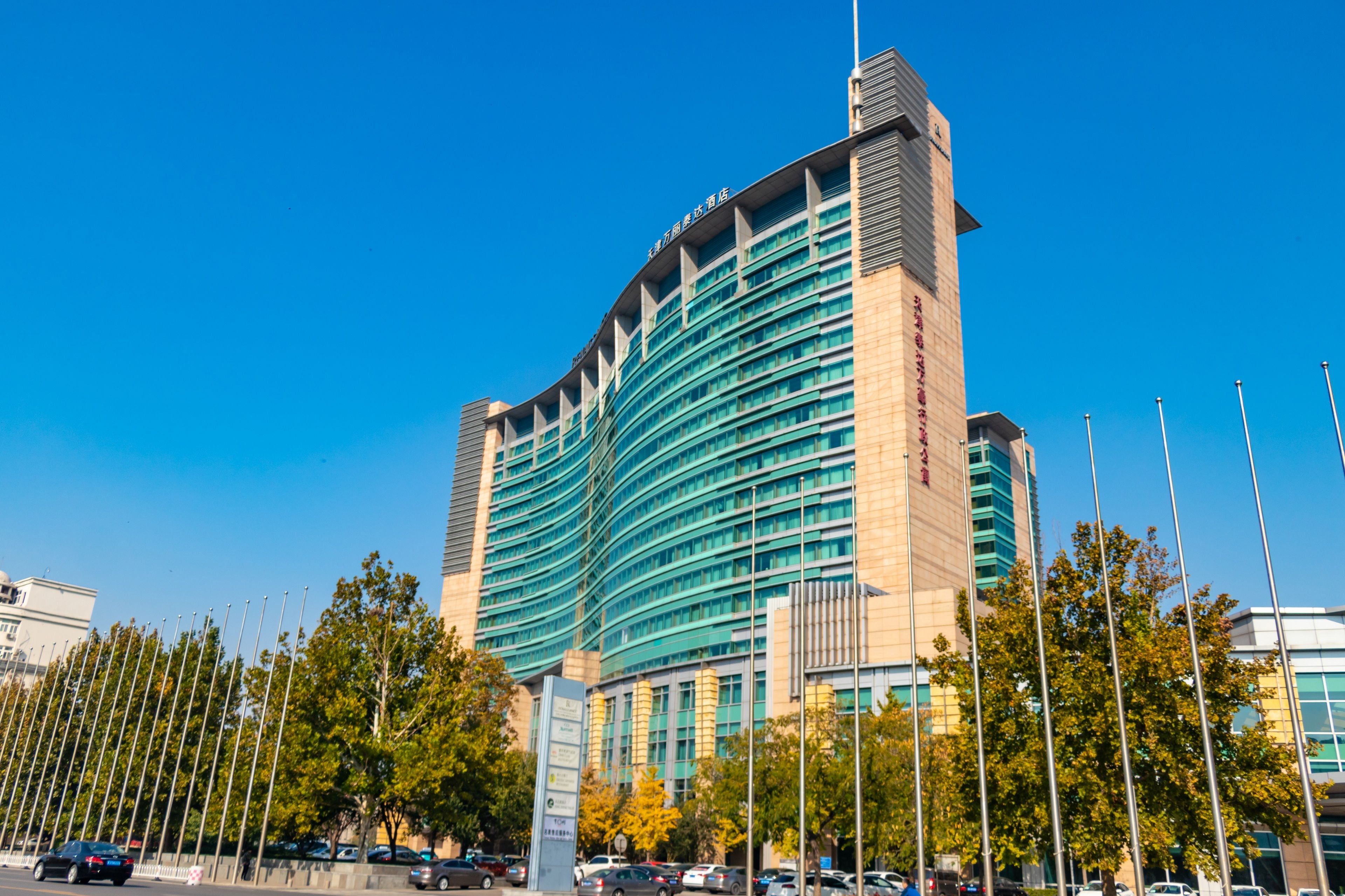 A modern hotel with a curved facade, multiple floors, and a prominent entrance.