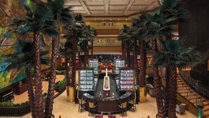 A spacious lobby with a central bar, surrounded by palm trees and seating areas.