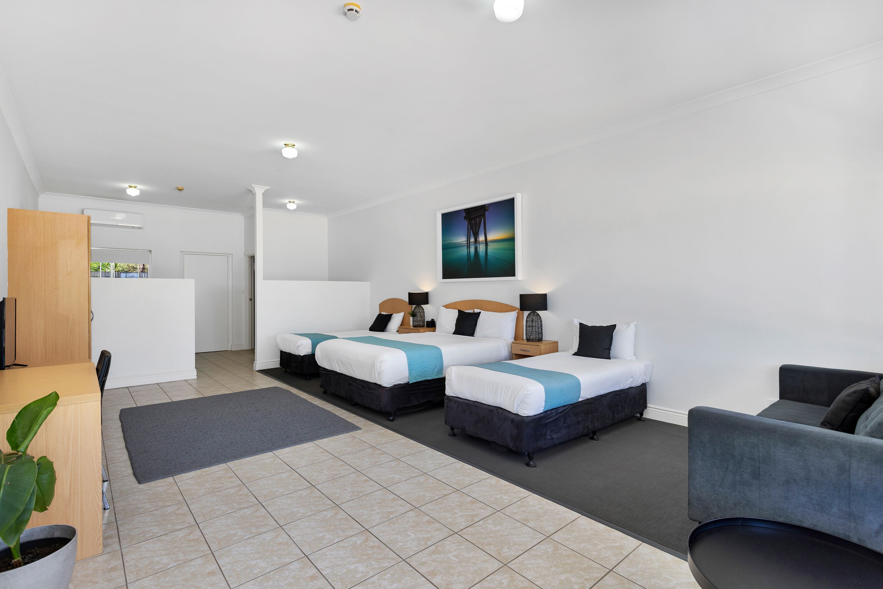 Een moderne hotelkamer met twee bedden, een bureau en een bank.