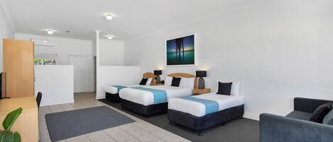 Een moderne hotelkamer met twee bedden, een bureau en een bank.