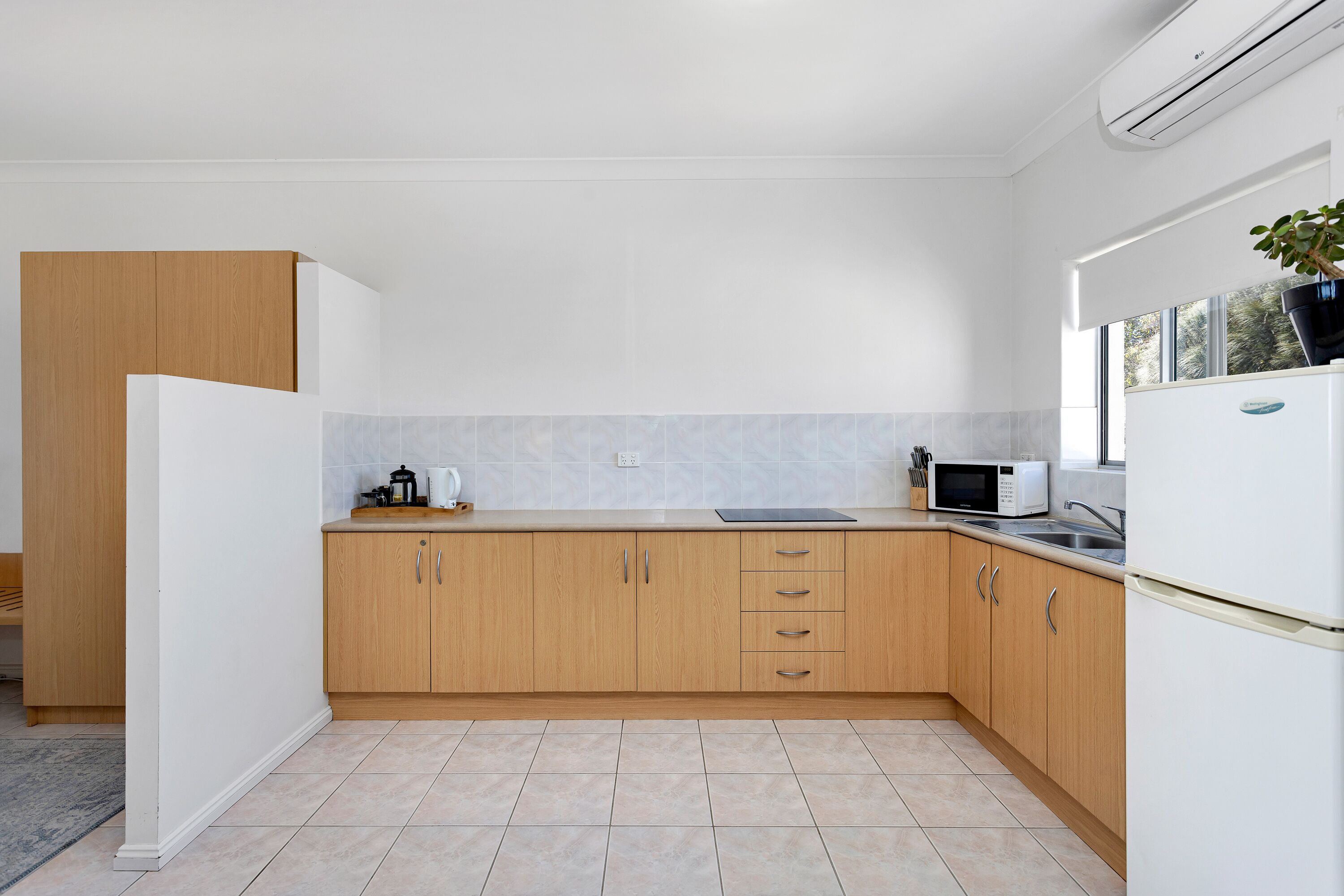 A modern kitchen with wooden cabinets, a microwave, and a refrigerator.