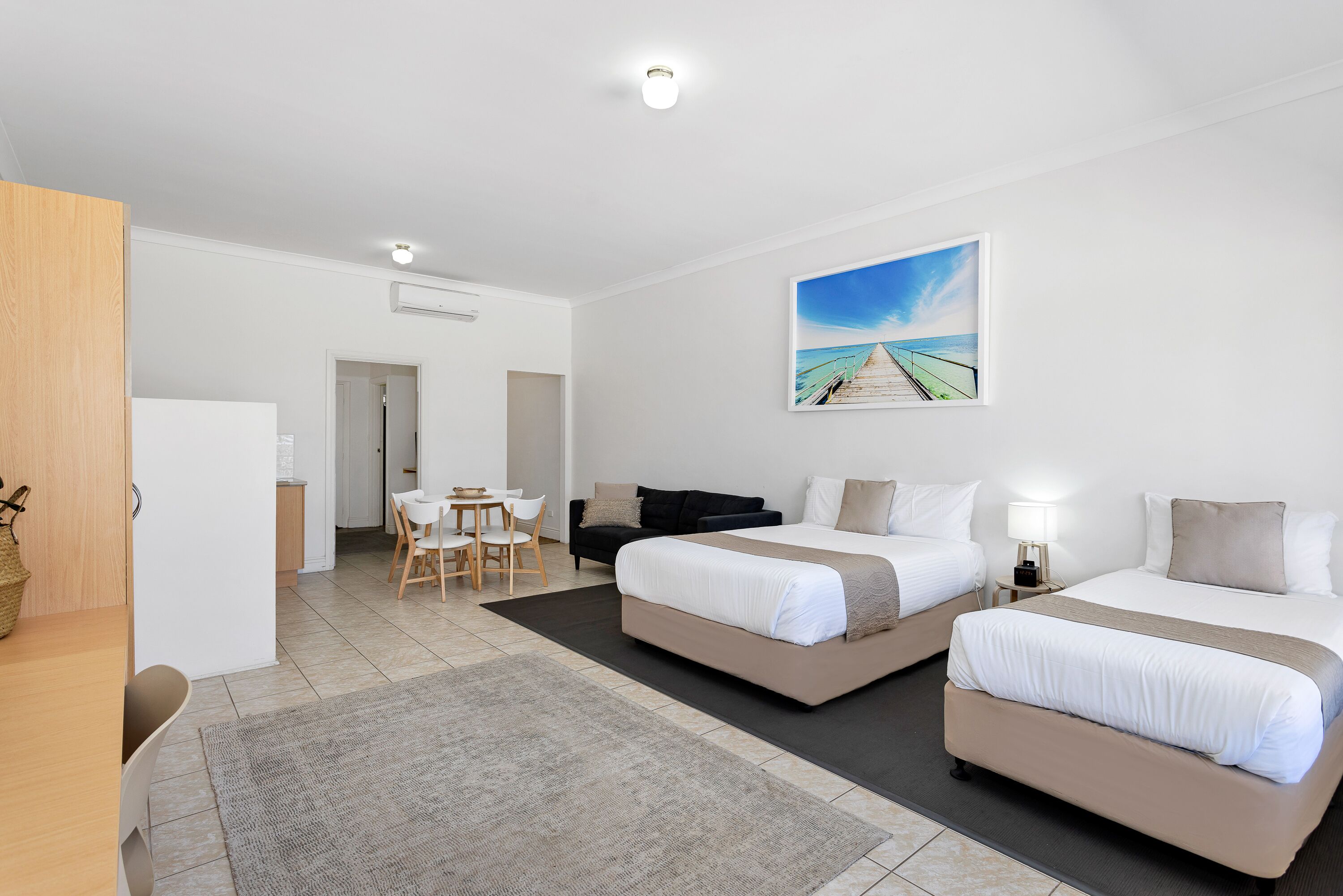 A hotel room with two beds, a desk, and a chair.
