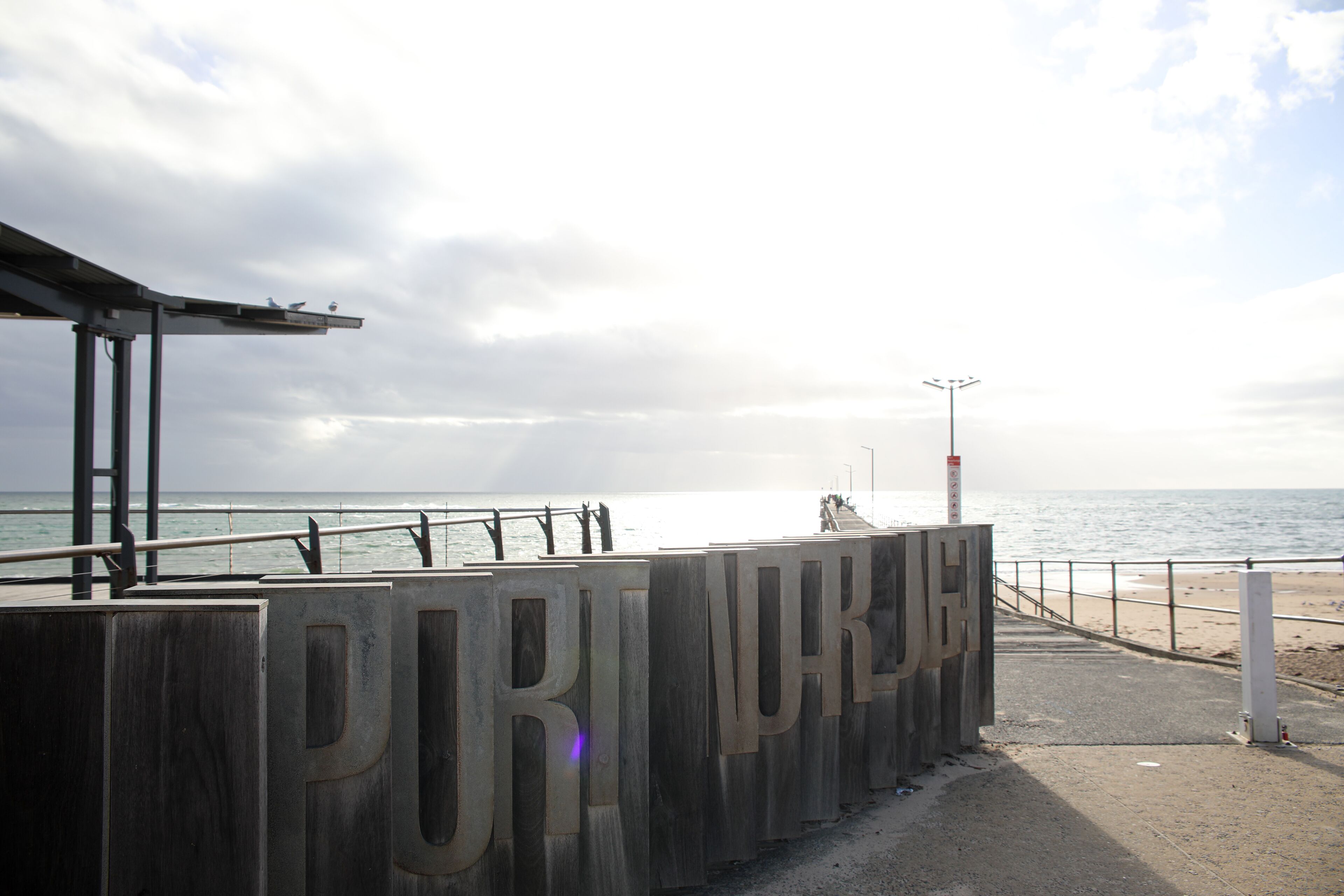 A wooden sign with the text "PULMURK" and a view of the beach and ocean.