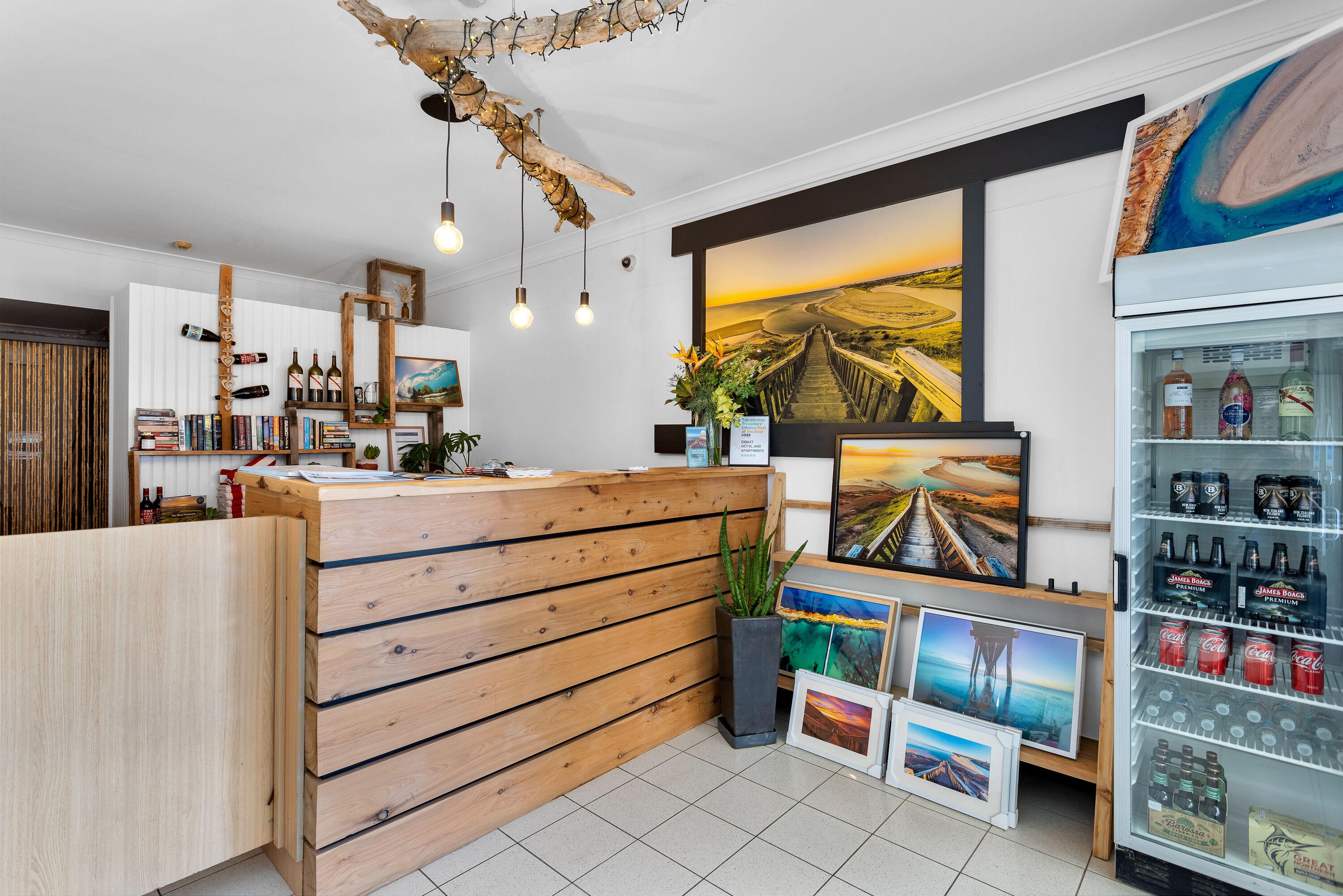 Una zona de recepción con un mostrador de madera, obras de arte enmarcadas y un refrigerador para bebidas.