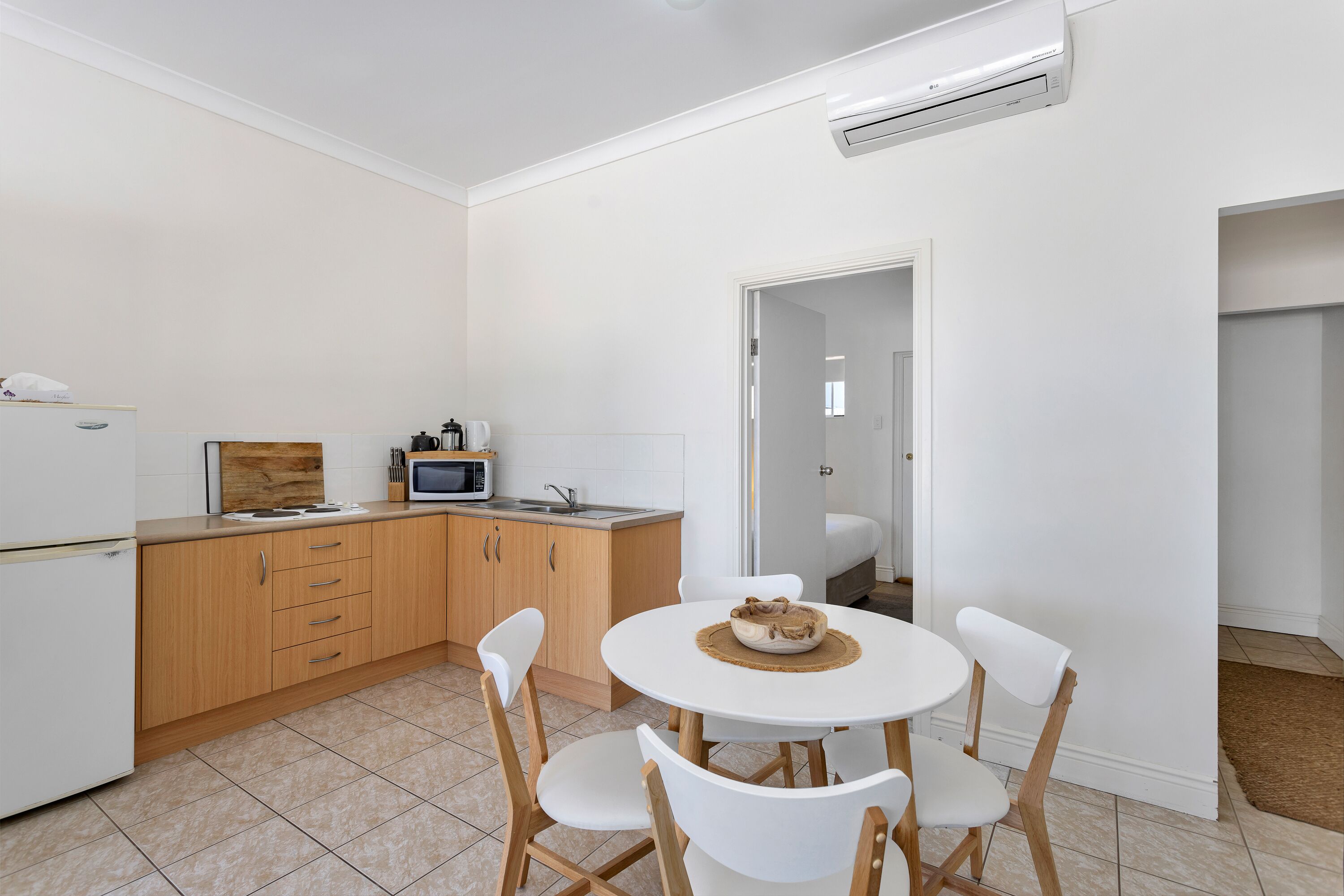 A compact kitchen with a dining area, featuring a microwave, sink, and wooden cabinets.