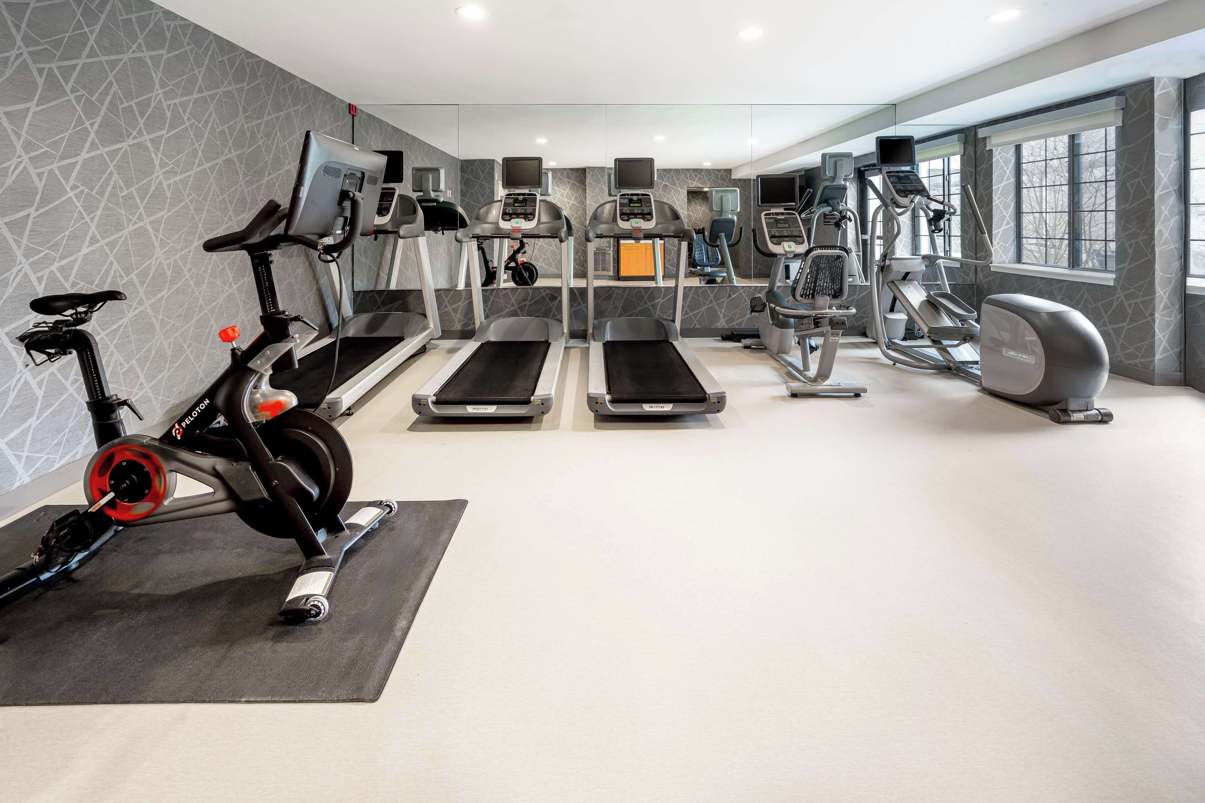 A modern gym with treadmills, elliptical machines, and a stationary bike.