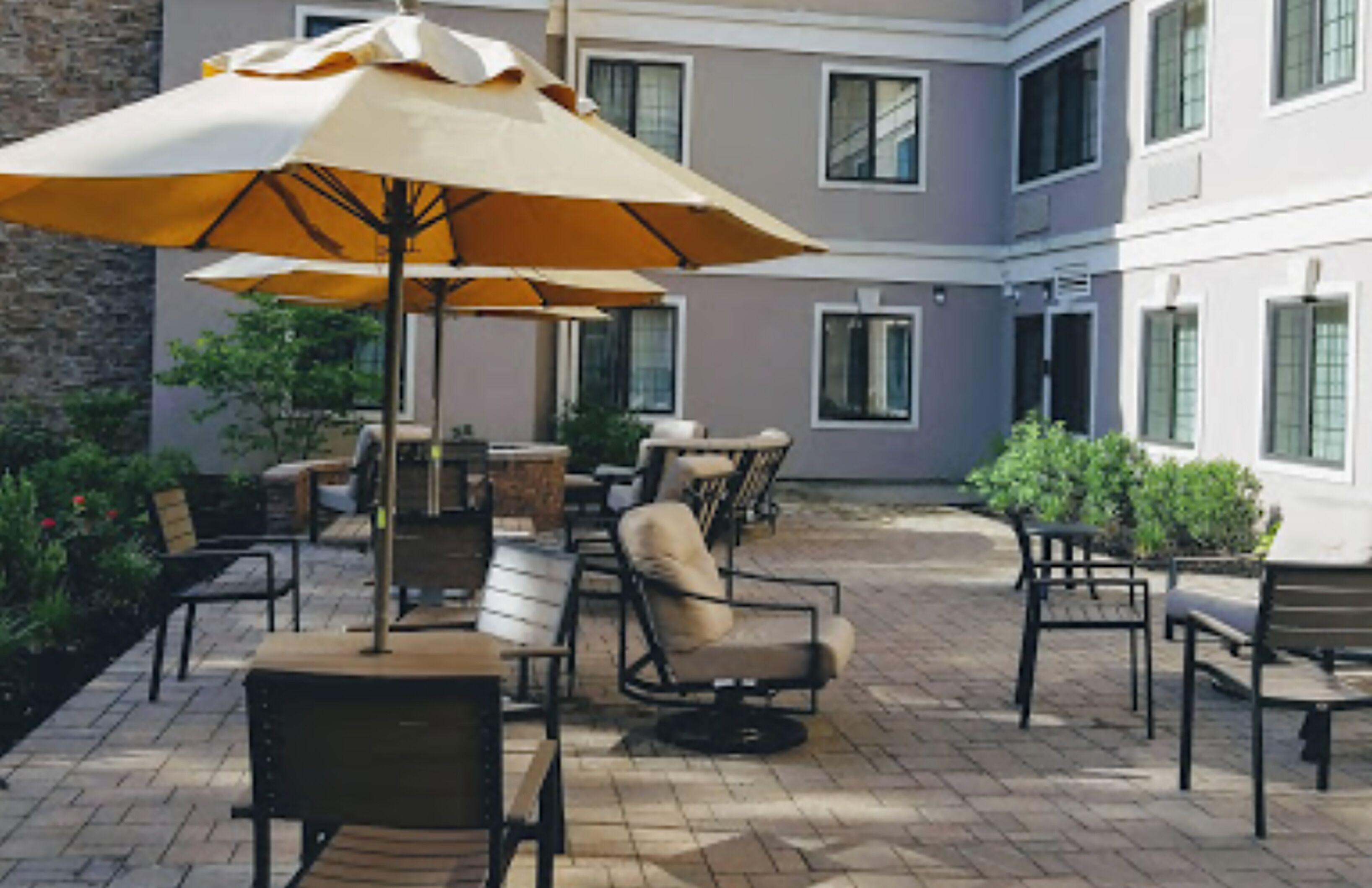 An outdoor patio area with multiple tables and chairs, some with umbrellas.