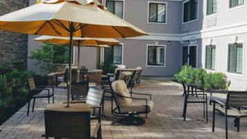An outdoor patio area with multiple tables and chairs, some with umbrellas.