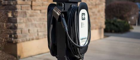 An electric vehicle charging station with a cable connected to it, mounted on a pole.