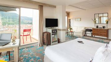 Une chambre d’hôtel avec un lit, un bureau avec un ordinateur portable, une télévision, une commode et une vue sur le paysage urbain.