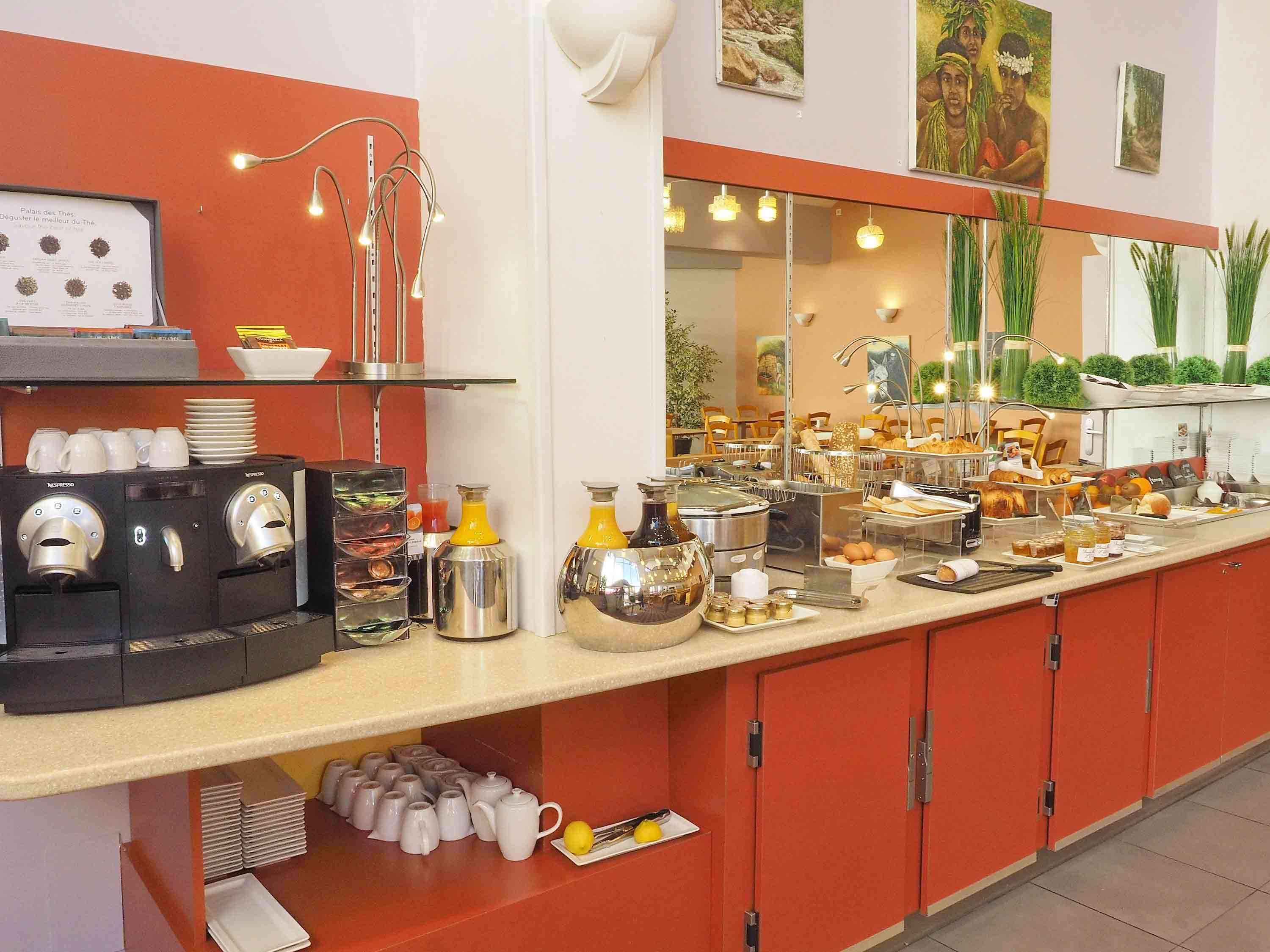 A buffet setup with coffee machines, a variety of food items, and a mirror reflecting the dining area.