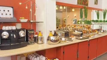 A buffet setup with coffee machines, a variety of food items, and a mirror reflecting the dining area.