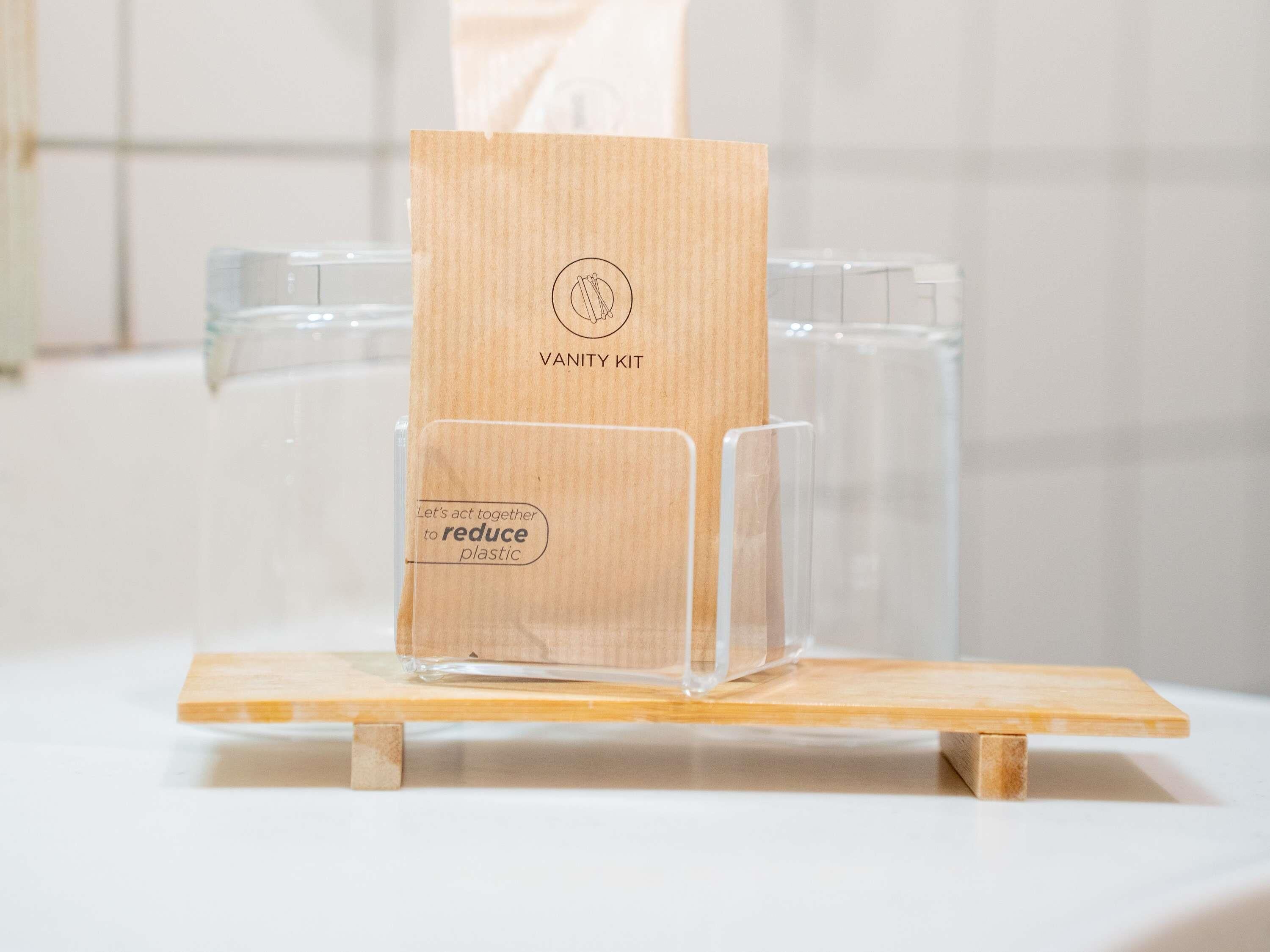 Un neceser con base de madera y un recipiente de plástico transparente.