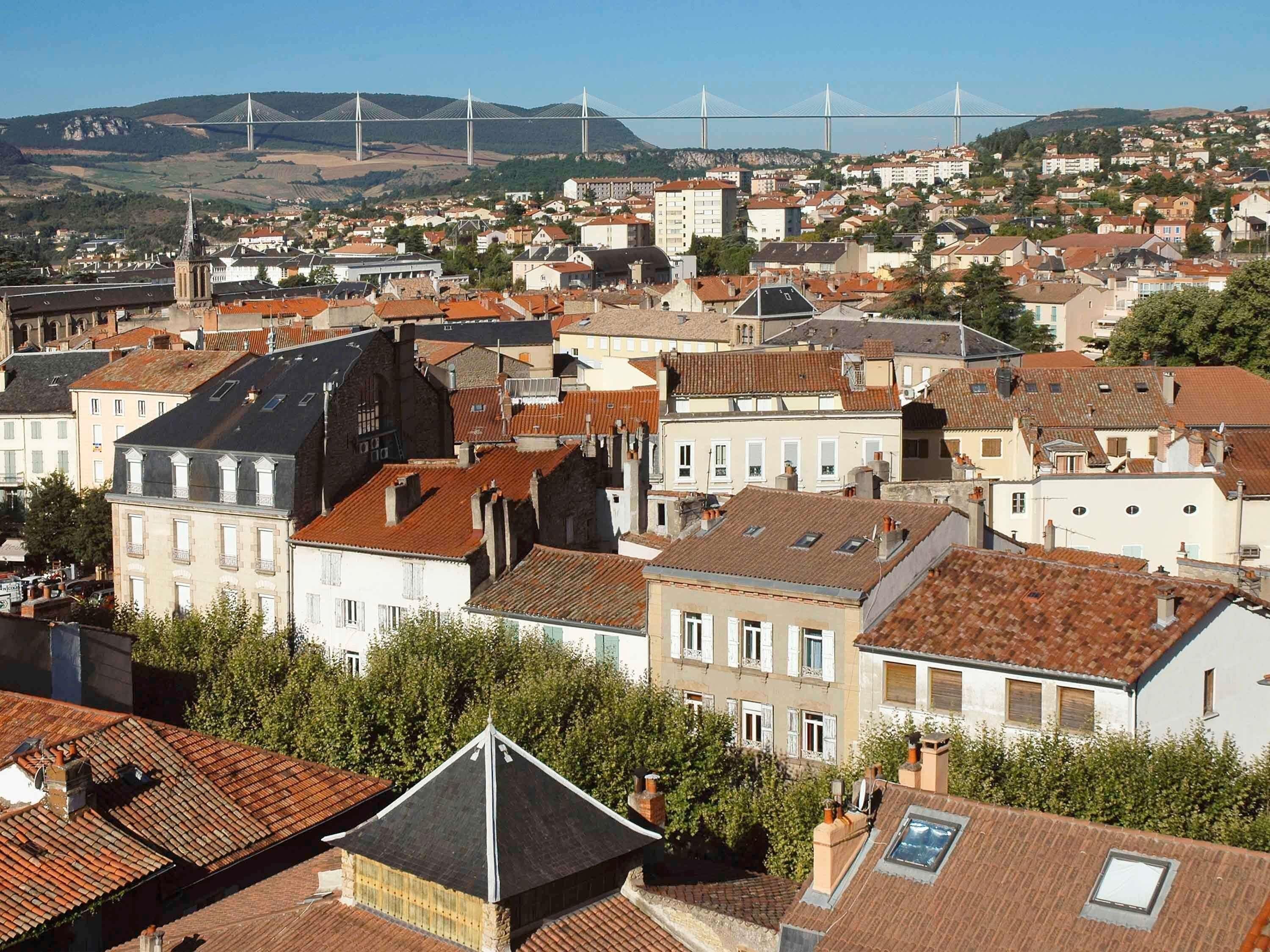 A cityscape with a prominent bridge in the background, dense residential buildings, and a mix of architectural styles.
