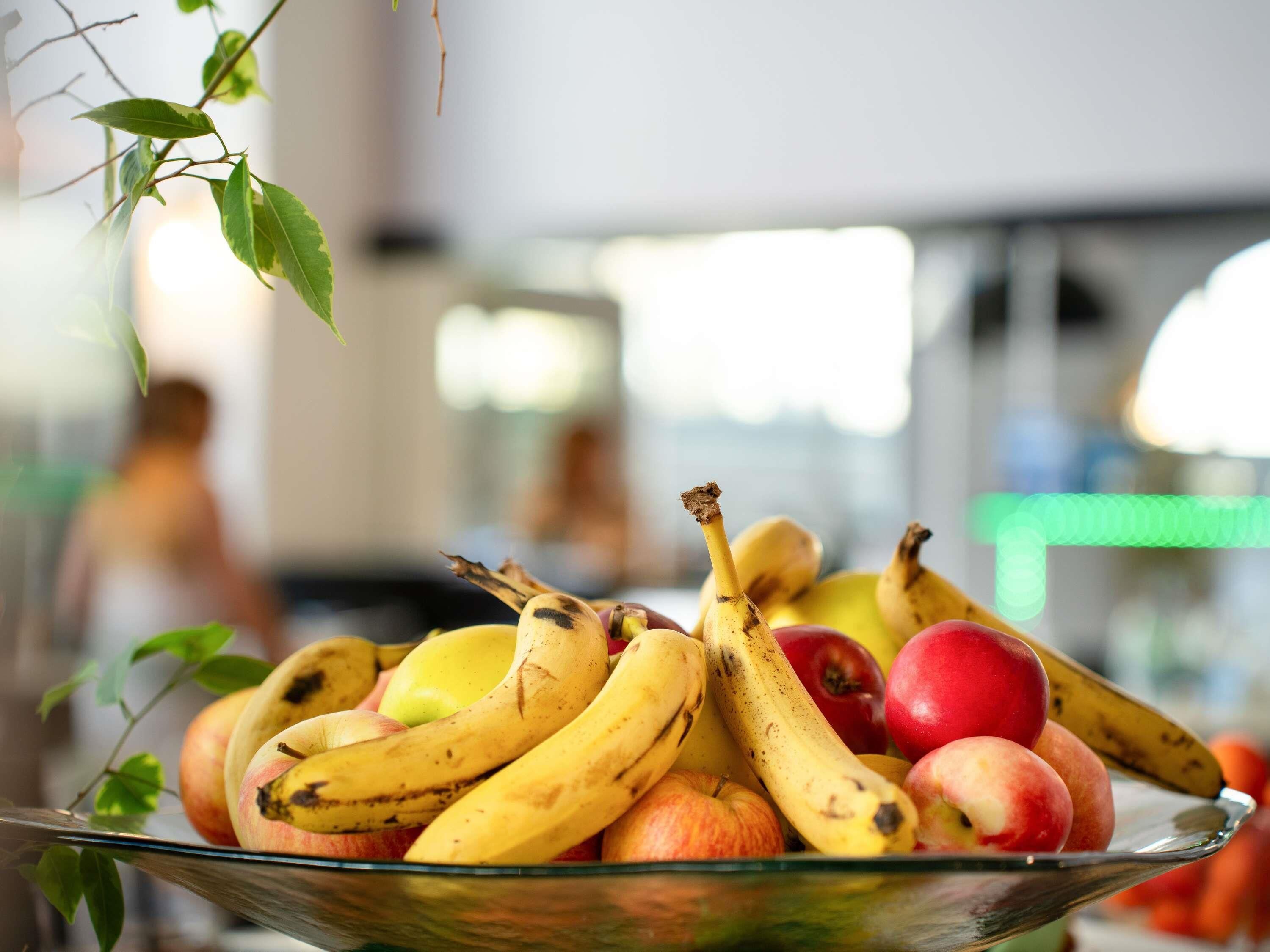 A bowl of fruit including bananas, apples, and peaches.